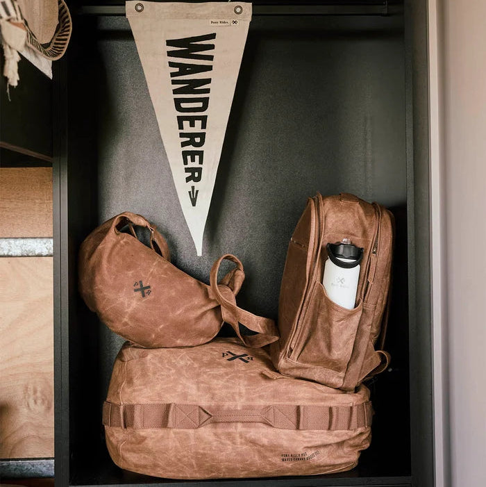 Brown travel bags and a pennant with Pony Rider 'Wanderer' on a shelf.