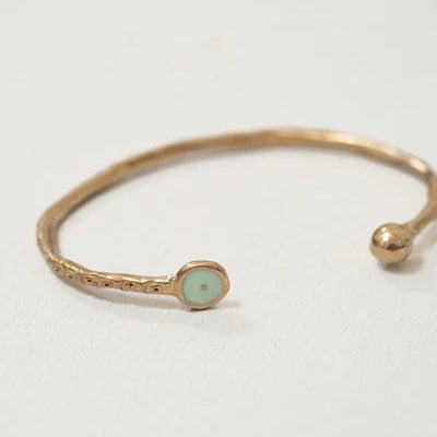 Bronze Pesci Che Volano bracelet with a small round green gemstone on a light gray background