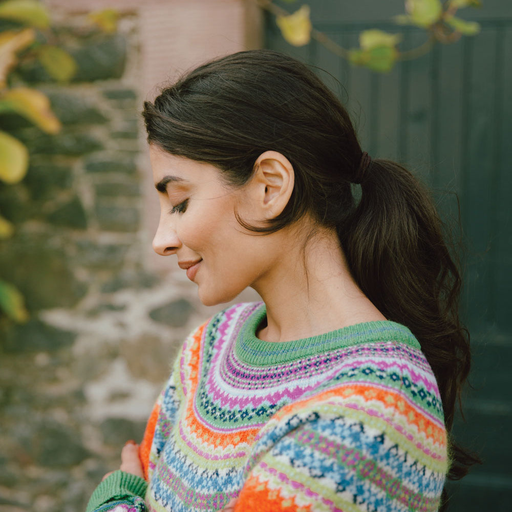 Woman wearing a Eribe cardigan standing against a stone wall.