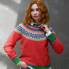 Person wearing a colorful Eribe sweater with a patterned yoke against a gray wall.