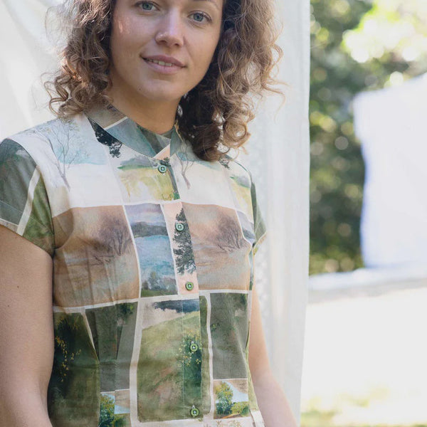 Woman wearing a shirt with a nature-themed patchwork design outdoors.