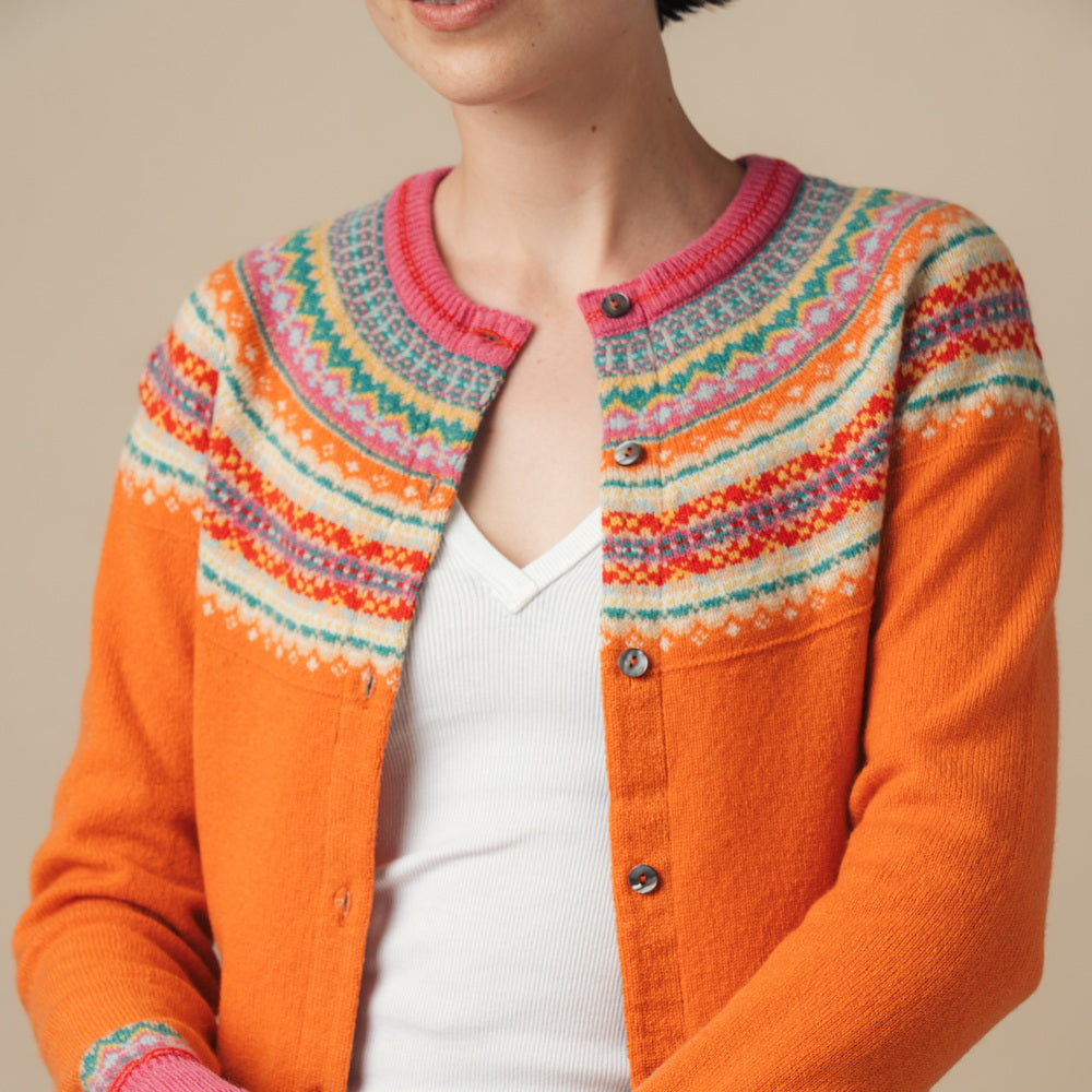Person wearing a colorful Eribe cardigan with a patterned design on a beige background