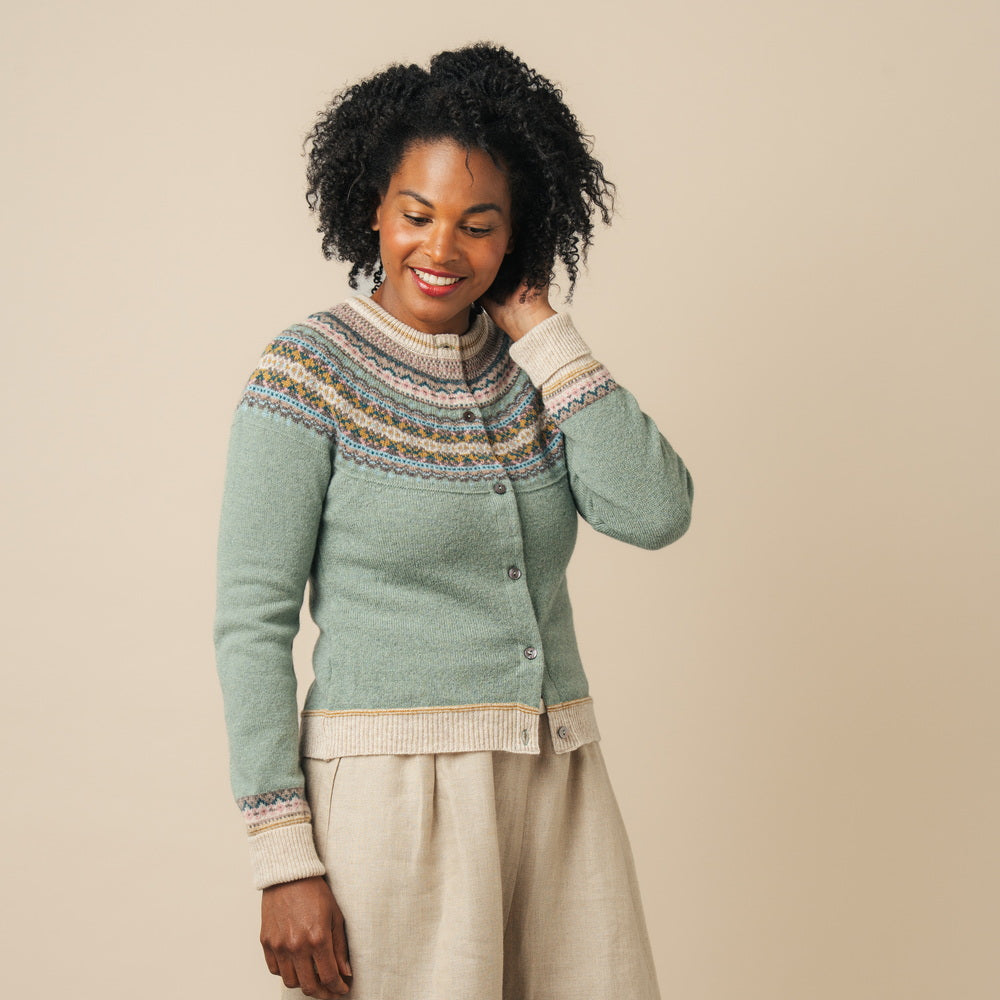 Woman wearing a patterned Eribe cardigan and beige pants against a beige background