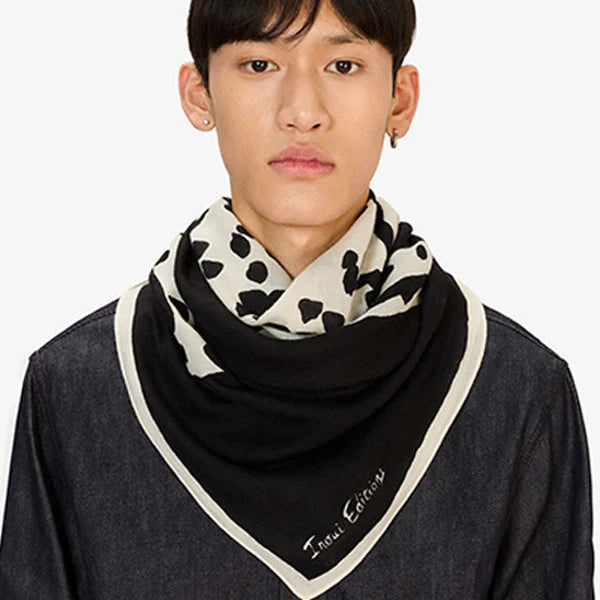 Person wearing a black and white patterned scarf on a plain background