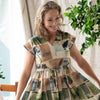 Woman wearing a patchwork dress with nature-themed prints indoors.
