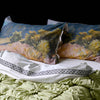 Green quilted blanket with scenic pillows on a black background