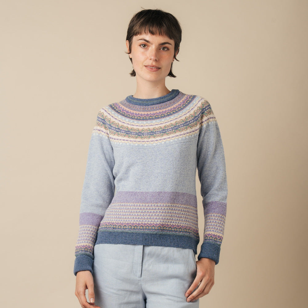 Person wearing a Eribe sweater and light pants against a beige background