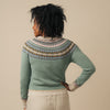 Person wearing a green Eribe sweater with a patterned yoke against a beige background