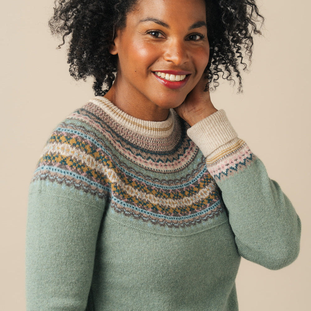Woman wearing a patterned Eribe sweater against a plain background