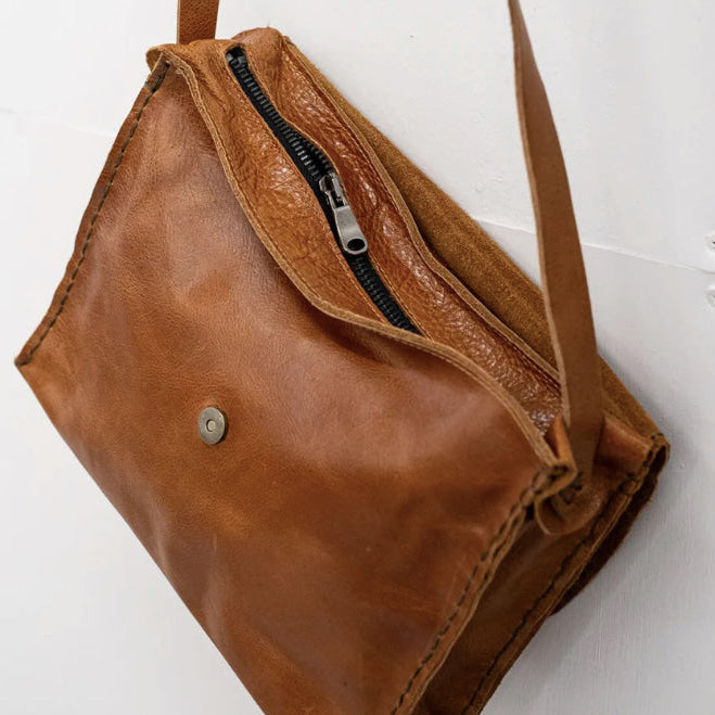 Brown leather bag with a zipper on a white background