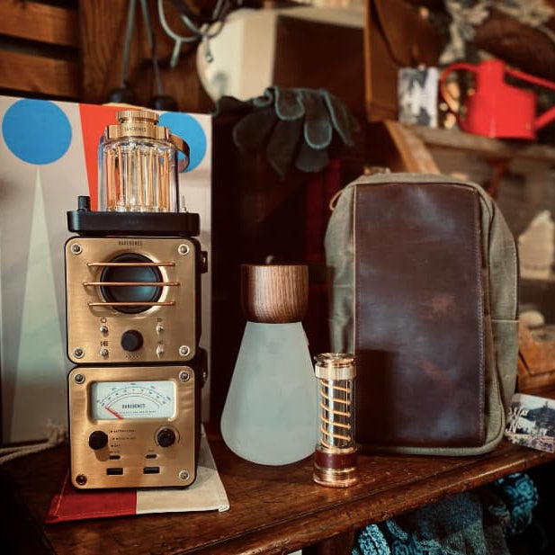Vintage-style radio receiver on a wooden surface with a leather pouch and other items in the background.