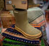 Merry People Andie Kids Gumboots - Green and yellow boot on a colorful scarf with a blurred background