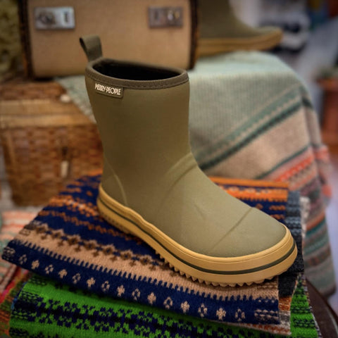 Merry People Andie Kids Gumboots - Green and yellow boot on a colorful scarf with a blurred background