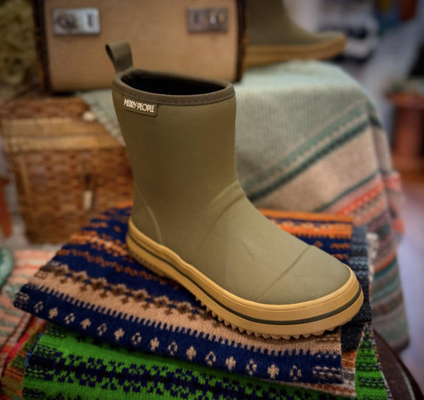 Merry People Andie Kids Gumboots - Green and yellow boot on a colorful scarf with a blurred background