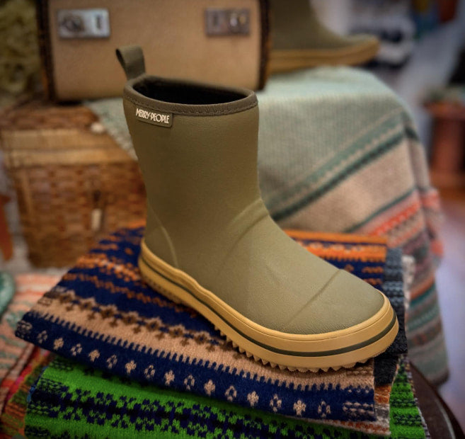 Merry People Andie Kids Gumboots - Green and yellow boot on a colorful scarf with a blurred background