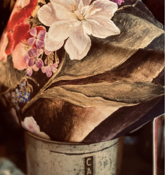 Floral arrangement cushion in a metal container with a blurred background
