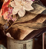Floral arrangement cushion in a metal container with a blurred background