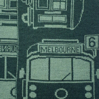 Close-up of a woven merino wool featuring vintage Melbourne tram and street signs in dark green and light sage green.