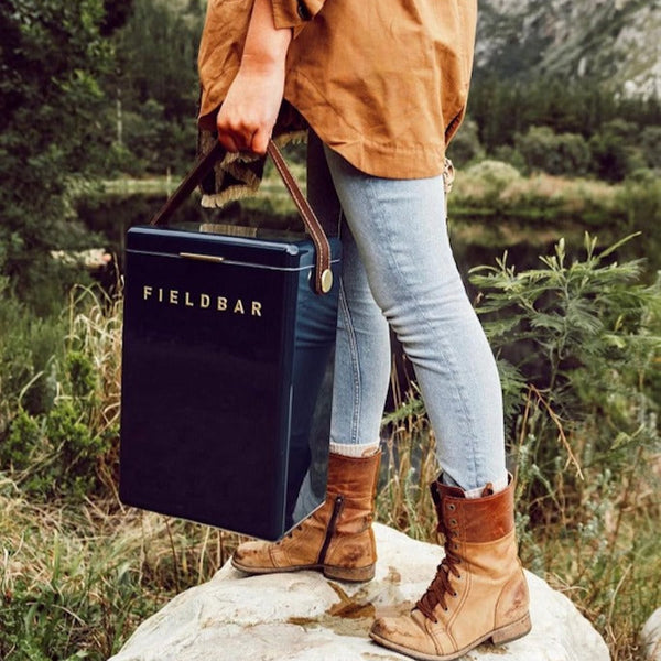 Person holding a 'Fieldbar' cooler bag in a natural setting