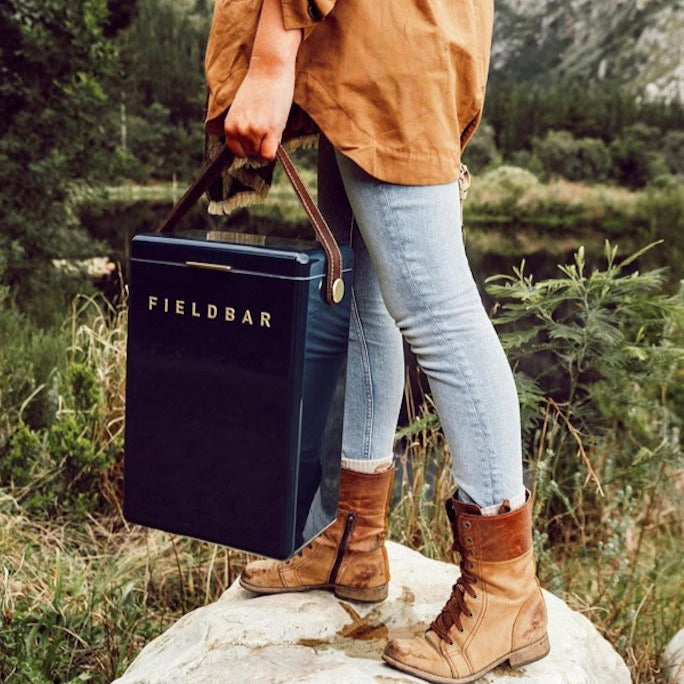 Person holding a 'Fieldbar' cooler bag in a natural setting