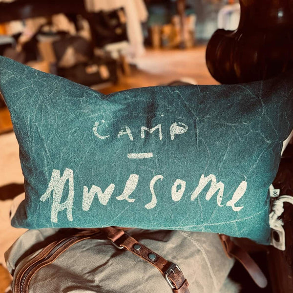 Teal pillow with 'Camp Awesome' text held by a person in an outdoor setting Pony Rider