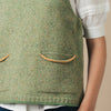 Green knitted vest with two front pockets worn over a white shirt and blue jeans.