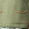 Green knitted vest with two front pockets worn over a white shirt and blue jeans.