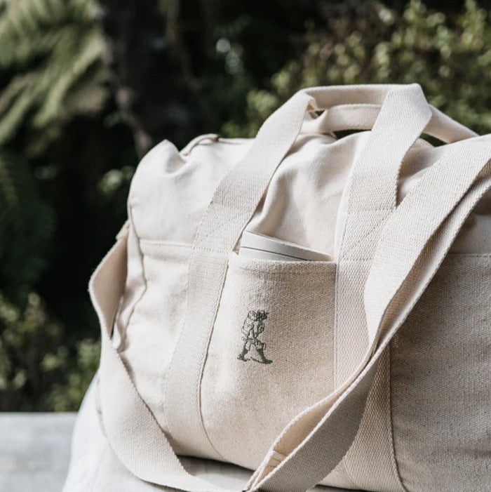 Beige canvas bag with a logo on a blurred natural background
