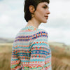 Person wearing a colorful patterned Eribe Mural sweater in a natural setting