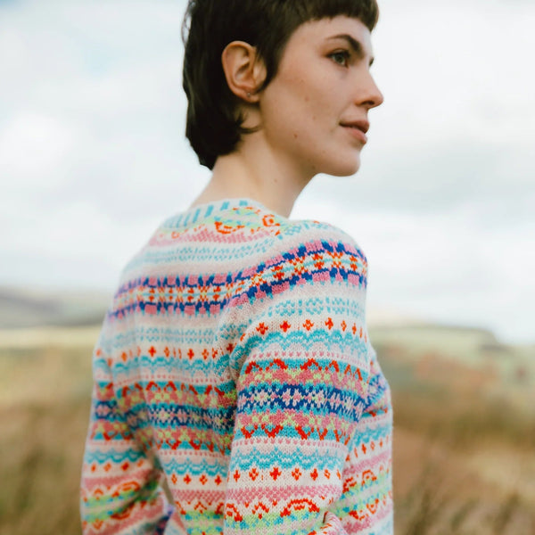 Person wearing a colorful patterned Eribe Mural sweater in a natural setting