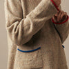 Beige sweater with red and blue accents worn by a person against a neutral background