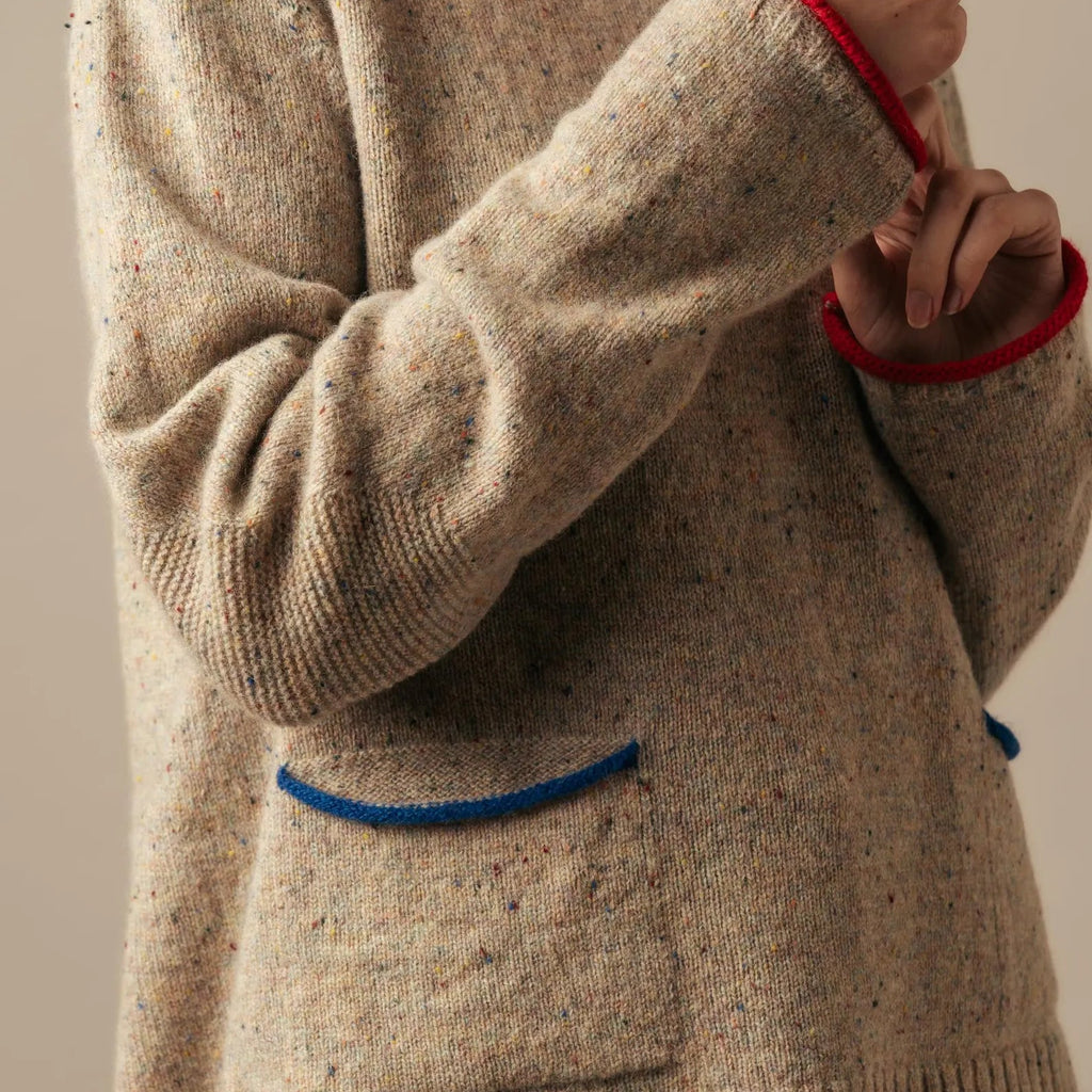 Beige sweater with red and blue accents worn by a person against a neutral background