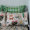 Floral and nature-themed pillows on a bed with floral bedding.