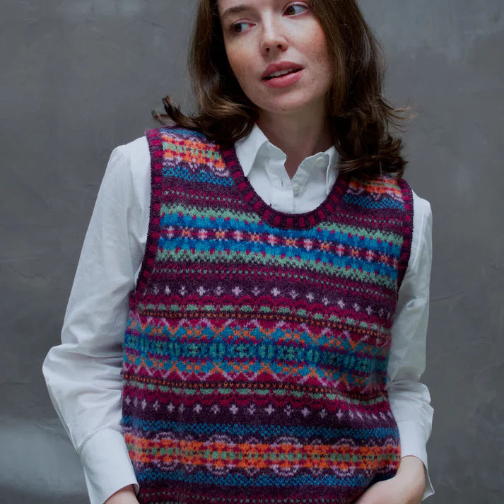 Woman wearing a colorful patterned Eribe vest against a gray background